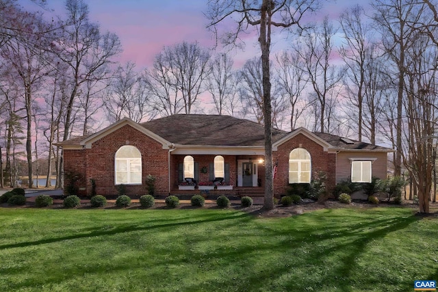 ranch-style house with brick siding, covered porch, and a front lawn