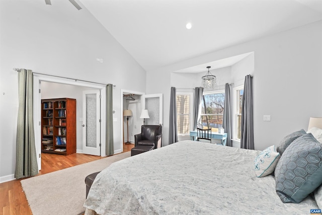 bedroom featuring high vaulted ceiling, baseboards, and wood finished floors