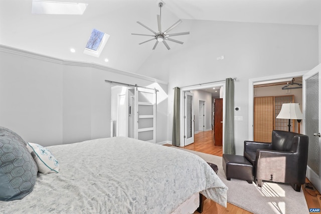 bedroom featuring ceiling fan, a skylight, wood finished floors, and high vaulted ceiling