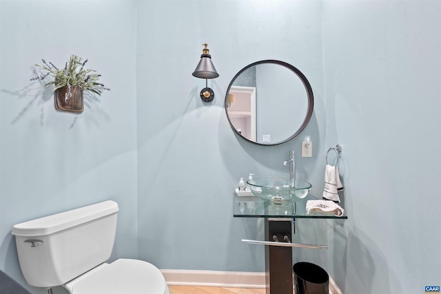 bathroom featuring tile patterned flooring, toilet, baseboards, and a sink