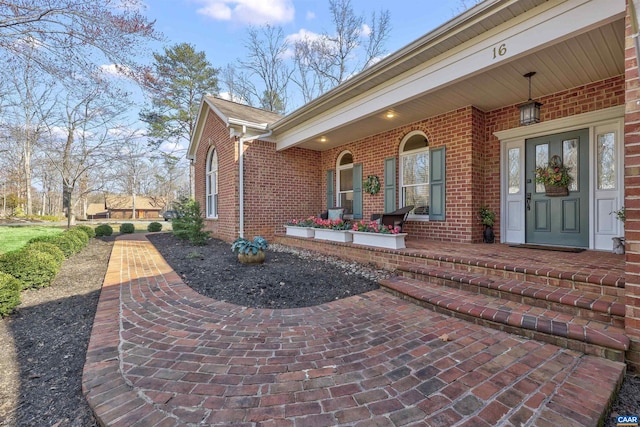 doorway to property featuring brick siding and covered porch