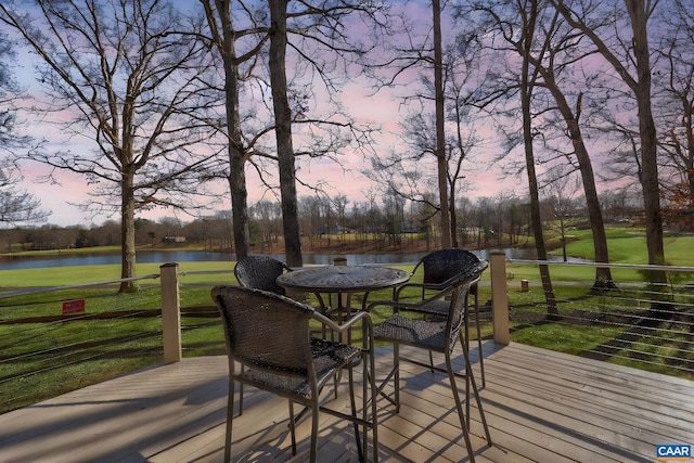 deck at dusk featuring a lawn and a water view