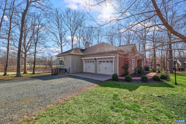 view of side of home featuring gravel driveway, an attached garage, a lawn, and a chimney