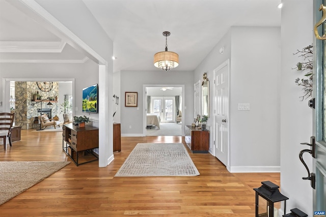 foyer entrance featuring a fireplace, baseboards, light wood-type flooring, and a ceiling fan