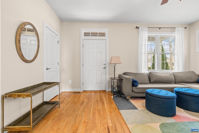 living area with light wood-style flooring, baseboards, and ceiling fan