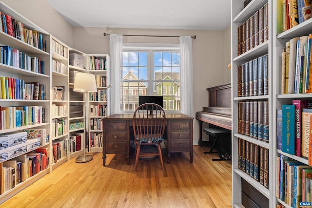 office space featuring wood finished floors and wall of books