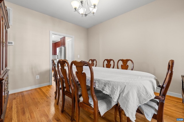 dining space with baseboards, light wood-style floors, and a chandelier