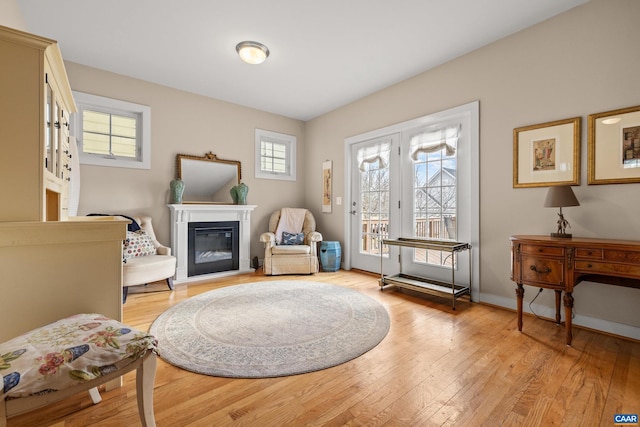 entryway with light wood-style flooring, baseboards, and a glass covered fireplace