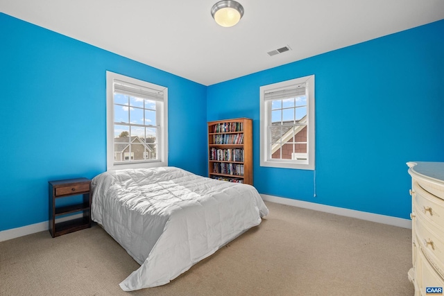 carpeted bedroom with multiple windows, baseboards, and visible vents