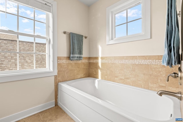 full bath featuring tile patterned floors, a bath, and baseboards