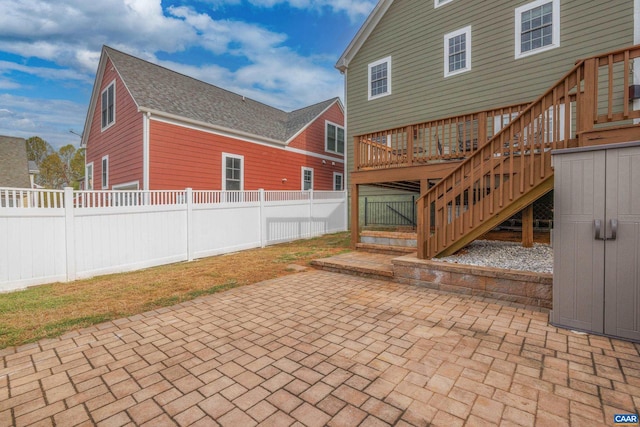 rear view of house featuring stairs, a deck, a patio area, and a fenced backyard