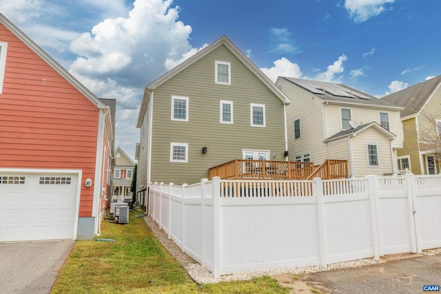 back of property featuring central air condition unit, a wooden deck, a garage, and fence