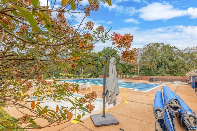 community pool with a patio and fence