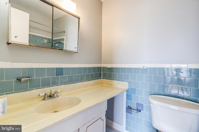 bathroom with a wainscoted wall, toilet, and vanity