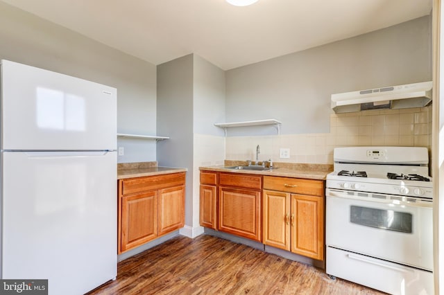 kitchen with under cabinet range hood, open shelves, a sink, wood finished floors, and white appliances