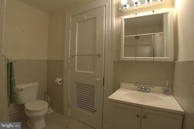 full bathroom with toilet, vanity, wainscoting, tile patterned floors, and tile walls