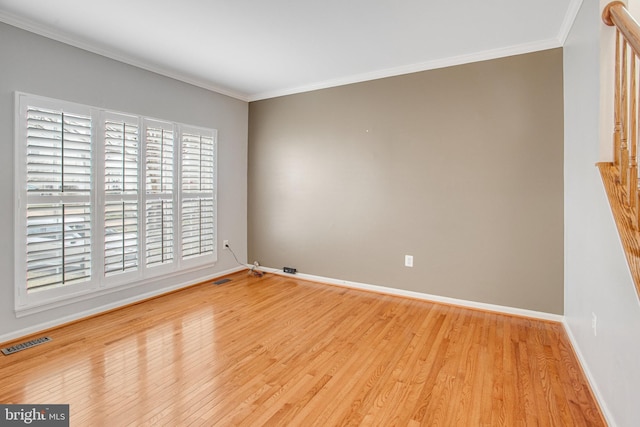 empty room featuring visible vents, baseboards, crown molding, and light wood-style floors