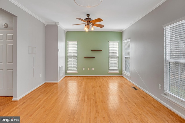 unfurnished living room featuring a wealth of natural light, visible vents, wood finished floors, and crown molding