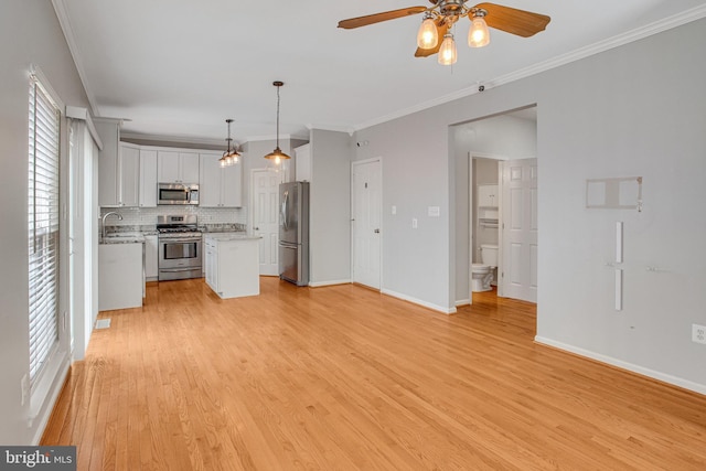 kitchen featuring ornamental molding, stainless steel appliances, light wood-type flooring, and a sink