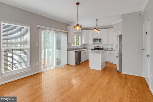 kitchen with a kitchen island, decorative backsplash, light wood-style flooring, stainless steel appliances, and white cabinetry