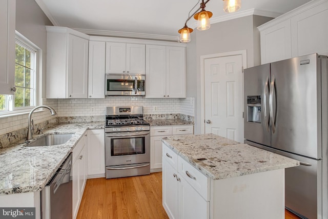 kitchen featuring crown molding, decorative backsplash, light wood-style flooring, appliances with stainless steel finishes, and a sink