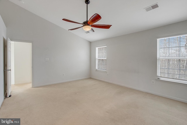 spare room with visible vents, baseboards, vaulted ceiling, light carpet, and a ceiling fan