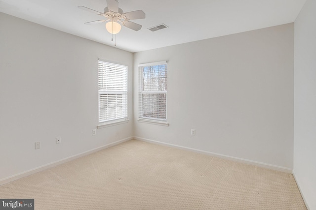 unfurnished room featuring visible vents, baseboards, light colored carpet, and ceiling fan