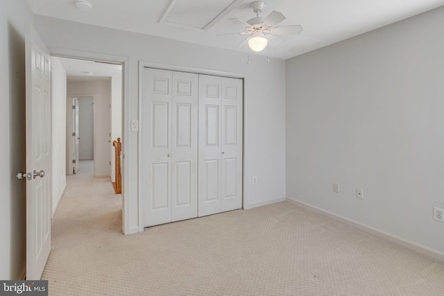 unfurnished bedroom with a closet, light colored carpet, and baseboards