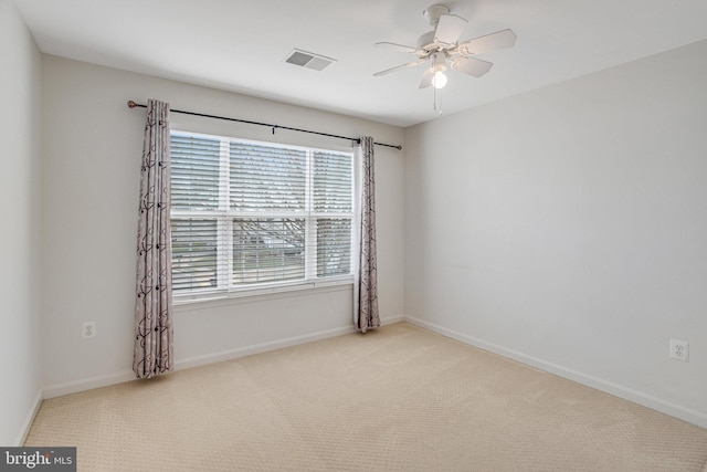 carpeted spare room featuring baseboards, visible vents, and ceiling fan