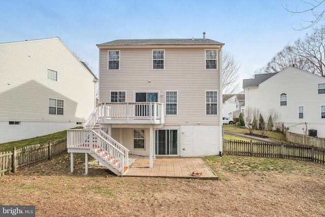 back of property with a fenced backyard, stairway, a wooden deck, brick siding, and a patio area