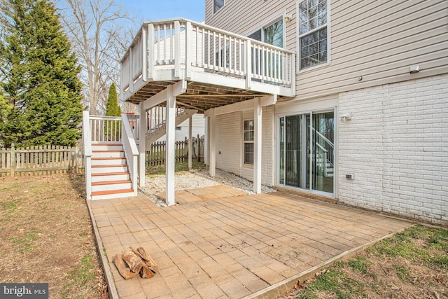 view of patio with a wooden deck, stairs, and fence