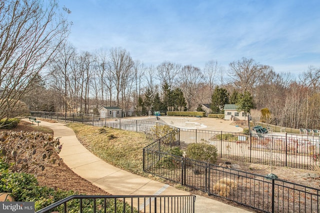 view of property's community with a patio, an outdoor structure, a pool, and fence