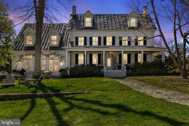 view of front of house with a fire pit, a lawn, covered porch, and a chimney