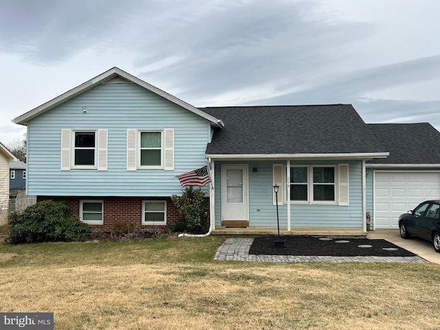 tri-level home with a garage, a front lawn, and roof with shingles