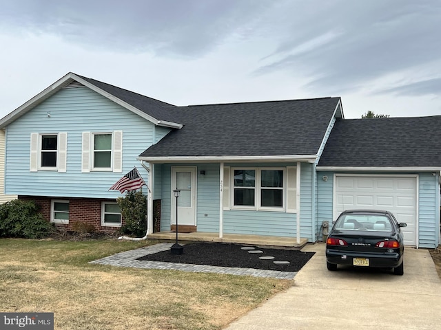 tri-level home featuring a front yard, a garage, driveway, and roof with shingles