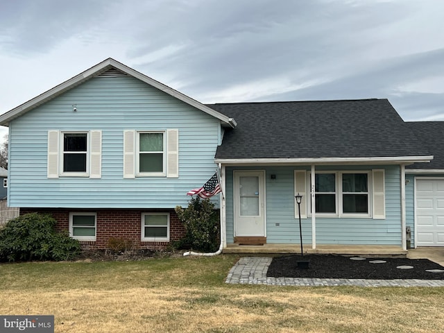 split level home featuring an attached garage, a front yard, and roof with shingles