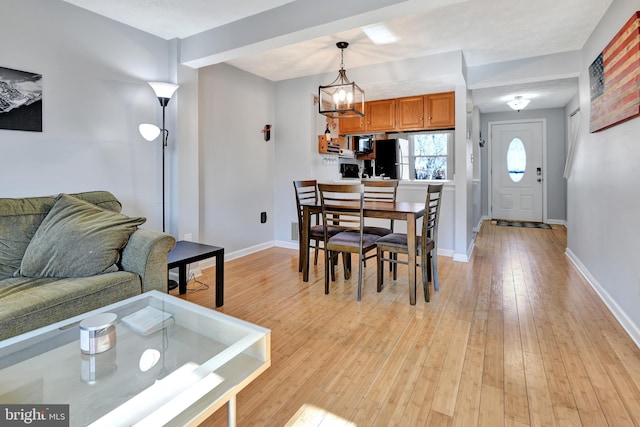 dining space with light wood finished floors, a chandelier, and baseboards