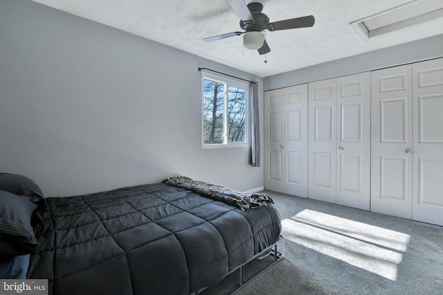 carpeted bedroom featuring a closet, a textured ceiling, attic access, and ceiling fan