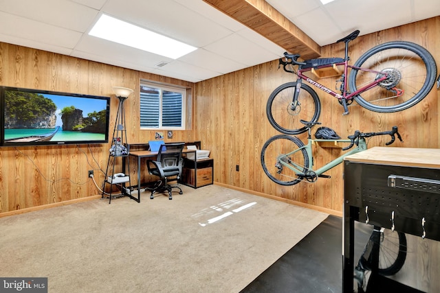 office space with carpet flooring, a drop ceiling, baseboards, and wood walls