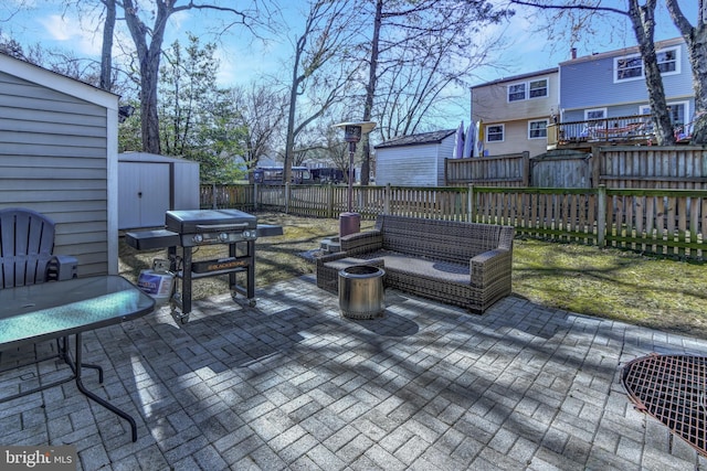 deck with a shed, a fenced backyard, an outdoor structure, area for grilling, and a patio