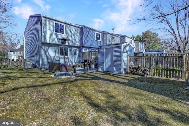 back of house featuring a fenced backyard, a yard, a storage shed, an outdoor structure, and central AC unit