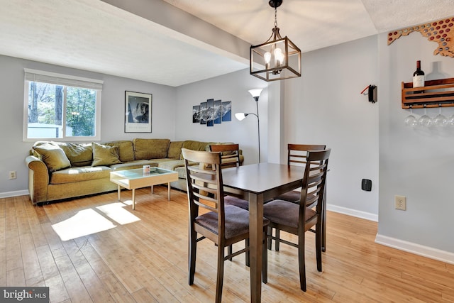 dining room featuring baseboards, a notable chandelier, and light wood finished floors