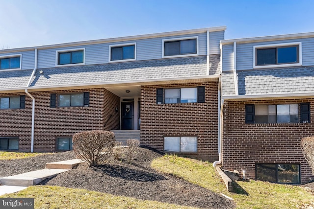 multi unit property with mansard roof, brick siding, and a shingled roof