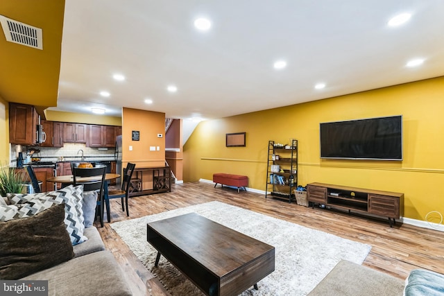 living area with light wood finished floors, visible vents, recessed lighting, and baseboards