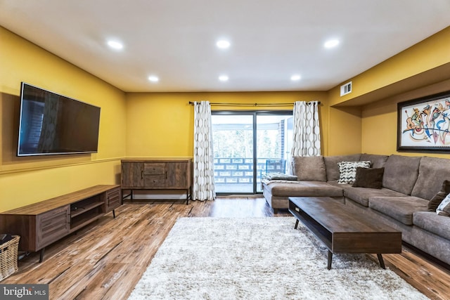 living area with recessed lighting, wood finished floors, and visible vents