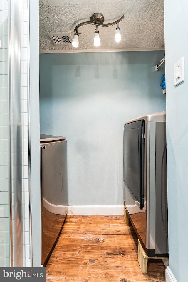 interior space with a textured ceiling, wood finished floors, and washing machine and clothes dryer