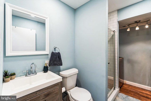 full bathroom with a shower stall, toilet, rail lighting, wood finished floors, and vanity