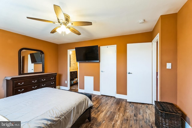 bedroom with dark wood finished floors, ensuite bath, baseboards, and ceiling fan