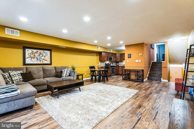 living area with stairway, recessed lighting, wood finished floors, and visible vents