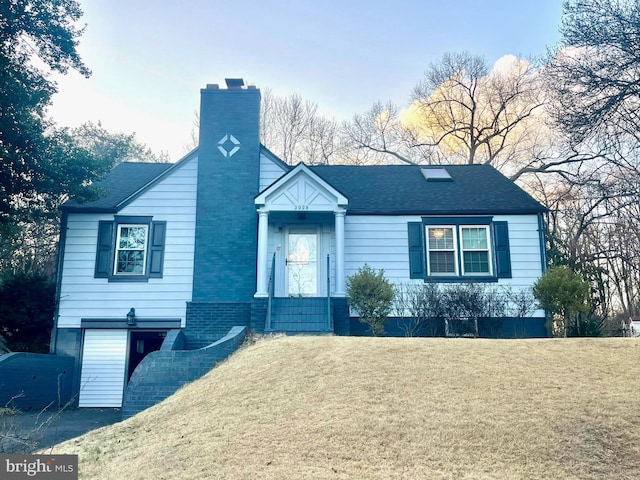 view of front facade featuring a chimney, a front yard, and a shingled roof